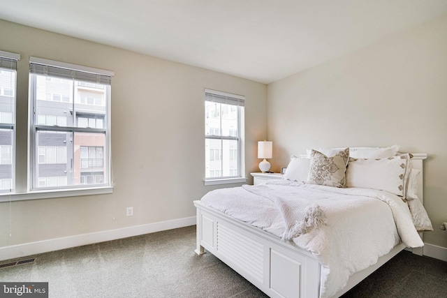 bedroom with visible vents, dark carpet, and baseboards