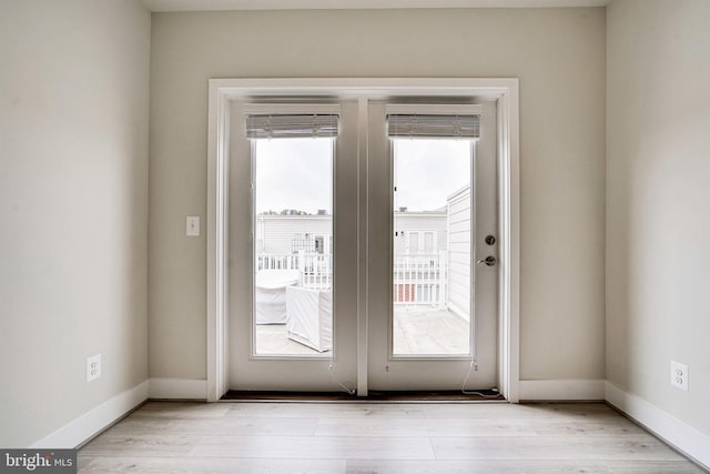 doorway with light wood-type flooring, plenty of natural light, and baseboards