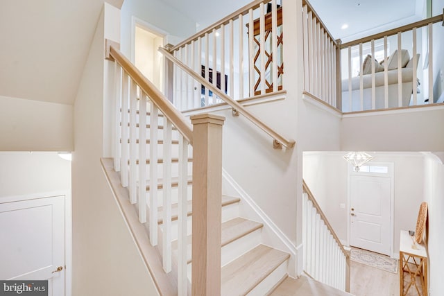 stairway with a high ceiling and wood finished floors