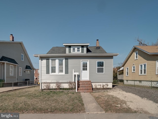 view of front facade featuring a shingled roof, a front lawn, fence, entry steps, and a chimney