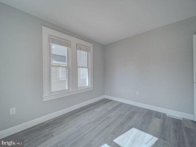 spare room with visible vents, wood finished floors, and baseboards