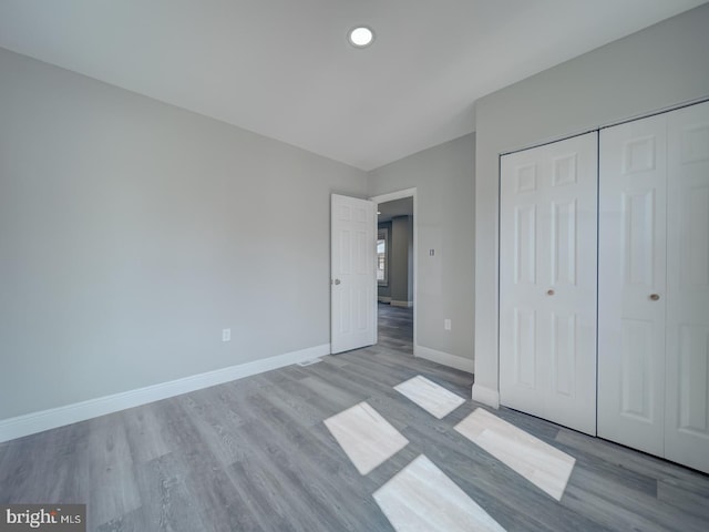 unfurnished bedroom featuring a closet, recessed lighting, baseboards, and wood finished floors