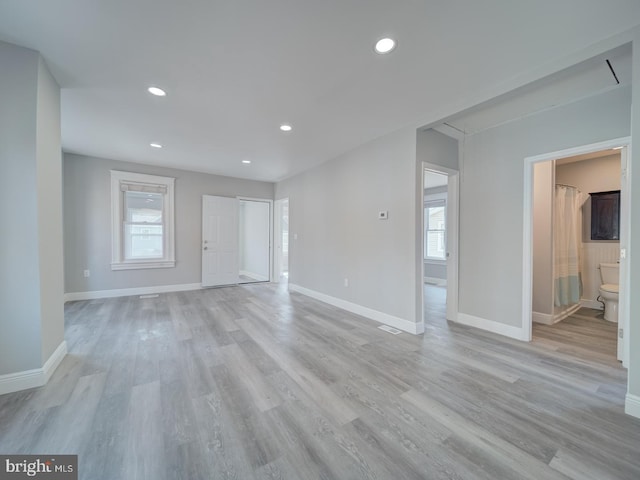 interior space with baseboards, light wood-style floors, and a healthy amount of sunlight