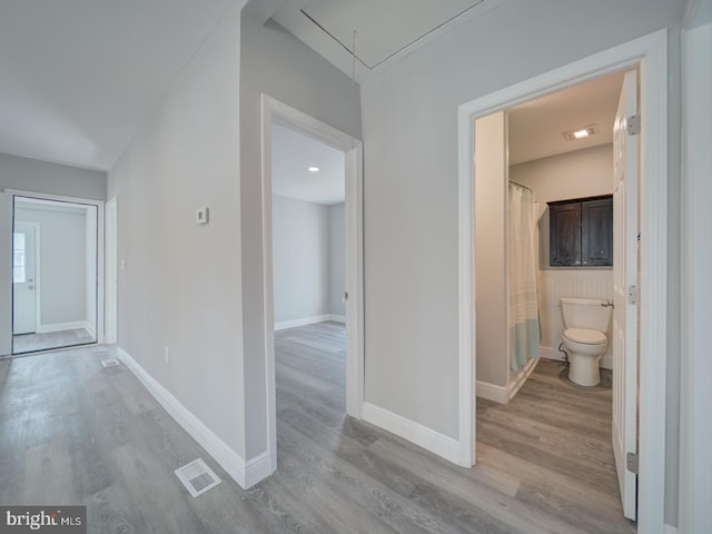 hallway with attic access, baseboards, visible vents, and light wood-type flooring