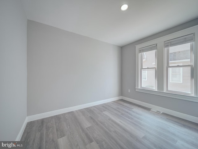 unfurnished room featuring visible vents, baseboards, and wood finished floors