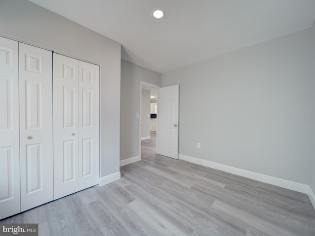 unfurnished bedroom with recessed lighting, a closet, baseboards, and light wood-style flooring