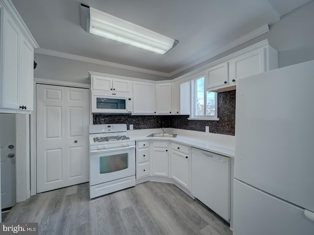 kitchen with ornamental molding, a sink, white appliances, light wood-style floors, and white cabinets