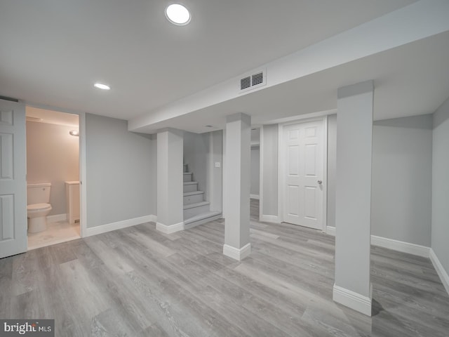 finished below grade area featuring visible vents, stairs, baseboards, and wood finished floors