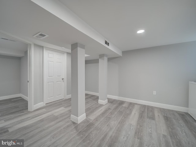 finished basement with visible vents, light wood-type flooring, and baseboards