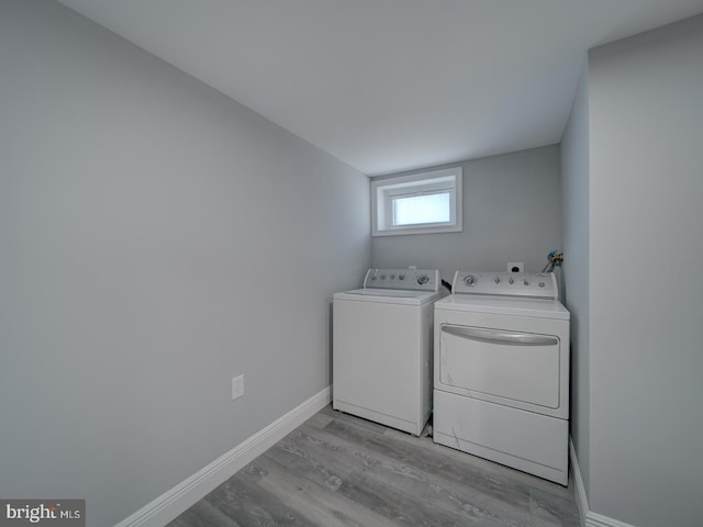 washroom with washer and dryer, baseboards, light wood-style flooring, and laundry area