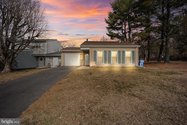 view of front facade with aphalt driveway, a lawn, and a garage