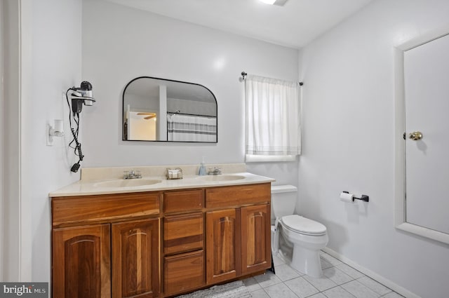 bathroom featuring tile patterned floors, toilet, double vanity, and a sink