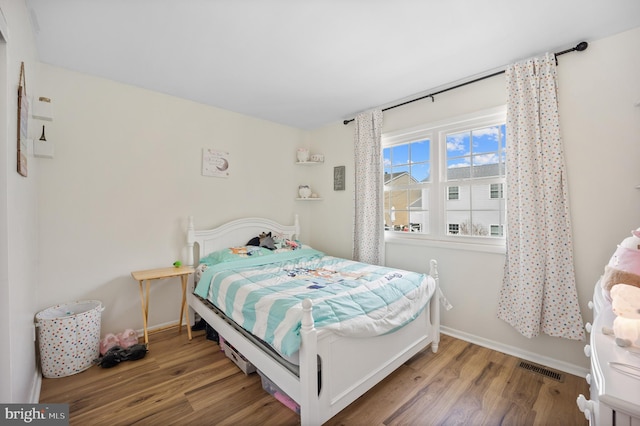 bedroom with visible vents, baseboards, and wood finished floors