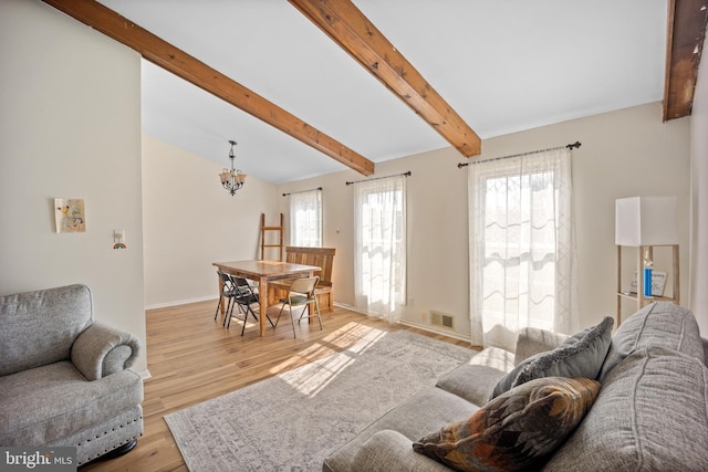 living room featuring baseboards, visible vents, lofted ceiling with beams, light wood-style flooring, and a chandelier