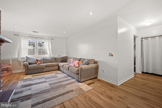 living area featuring visible vents, baseboards, and wood finished floors