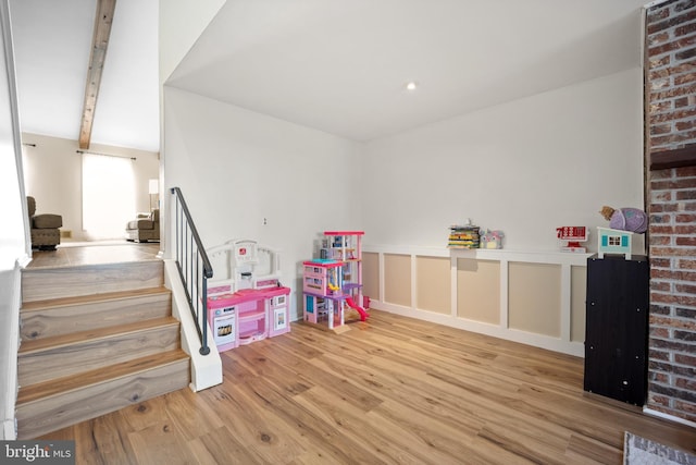 recreation room featuring beamed ceiling and wood finished floors