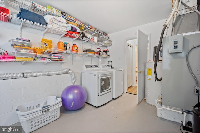 washroom with concrete block wall, washing machine and clothes dryer, water heater, and laundry area