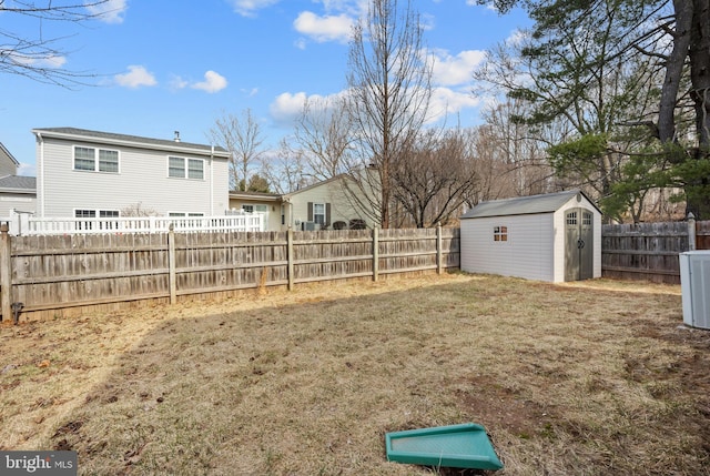 view of yard with a fenced backyard, central AC, a storage shed, and an outdoor structure