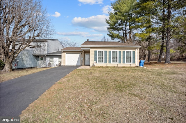 single story home with aphalt driveway, a garage, and a front lawn