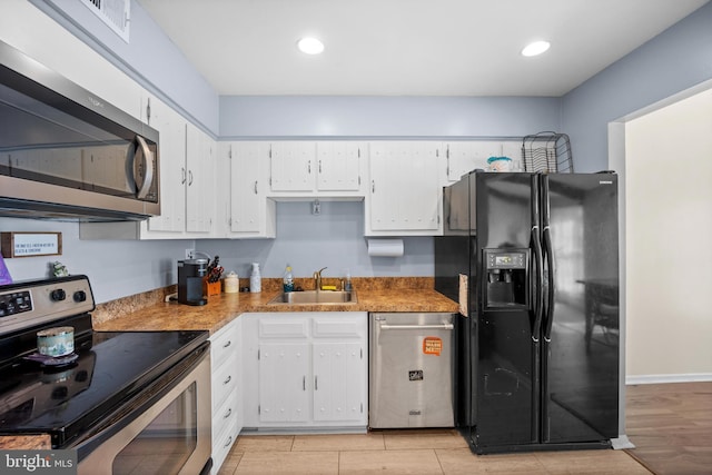 kitchen featuring light wood-style flooring, a sink, recessed lighting, appliances with stainless steel finishes, and white cabinets