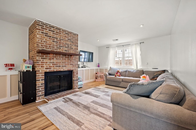 living room featuring a fireplace, wood finished floors, and visible vents