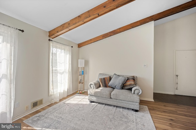 living room featuring visible vents, baseboards, wood finished floors, and vaulted ceiling with beams