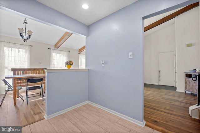 kitchen with baseboards, vaulted ceiling with beams, and light wood finished floors