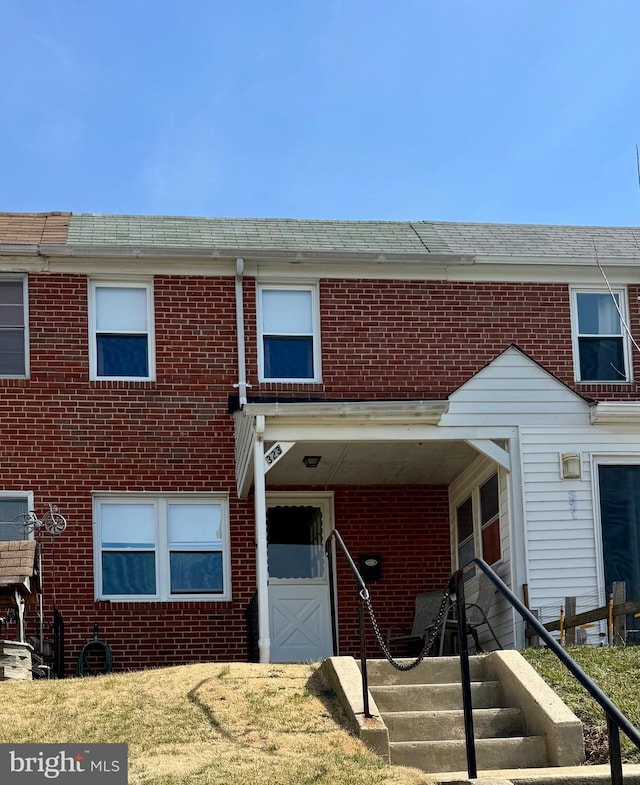 townhome / multi-family property with brick siding and roof with shingles