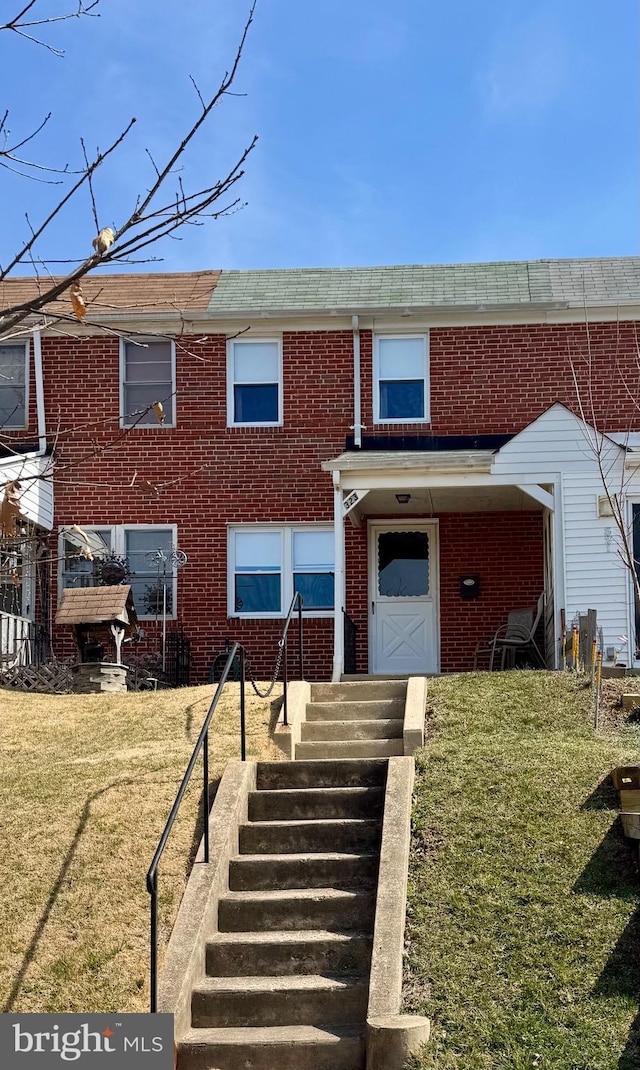 view of property featuring brick siding and a front yard