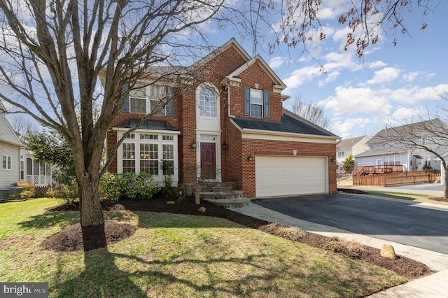 traditional-style home with brick siding, driveway, a front yard, and a garage