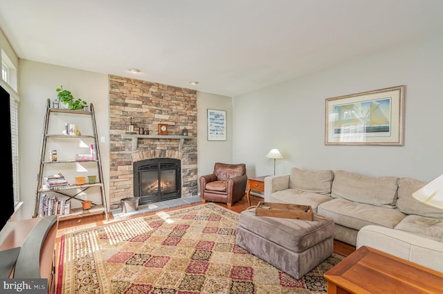 living room with a stone fireplace and wood finished floors