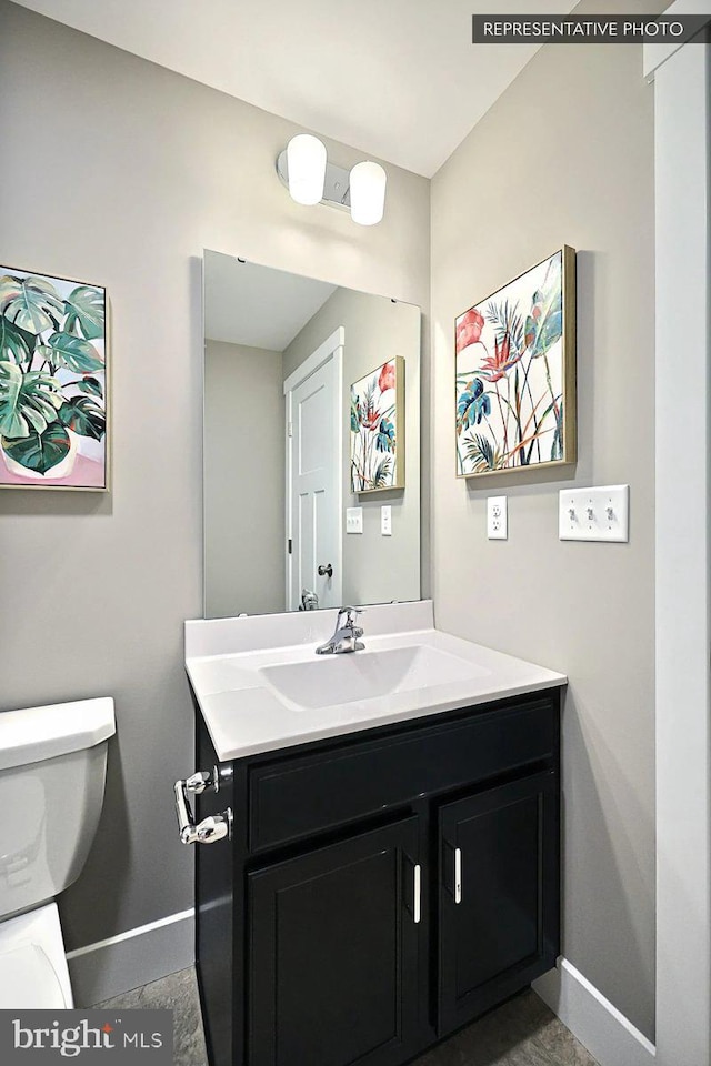 bathroom featuring baseboards, toilet, and vanity