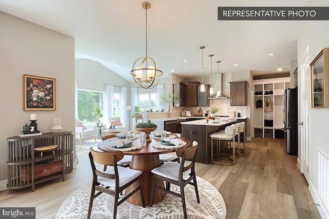 dining space with light wood finished floors, a notable chandelier, recessed lighting, and vaulted ceiling