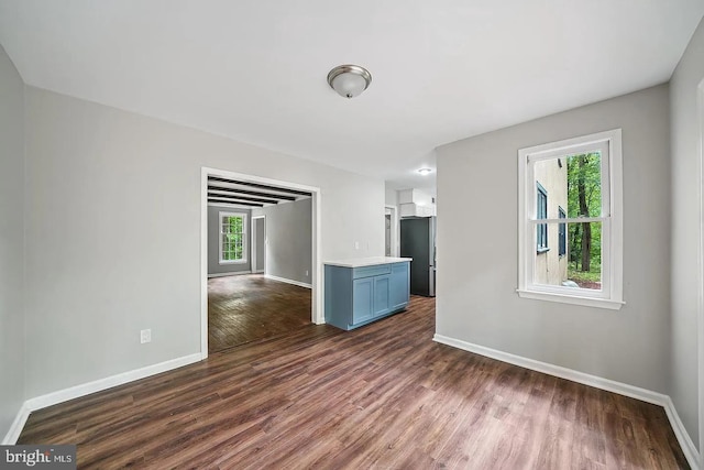 unfurnished room with dark wood-type flooring and baseboards