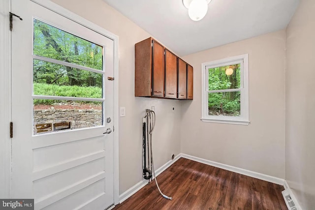 washroom with visible vents, hookup for an electric dryer, baseboards, cabinet space, and dark wood-style flooring