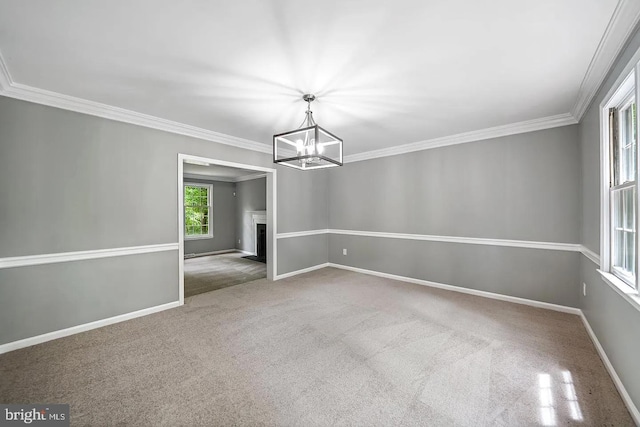 spare room with a notable chandelier, carpet, baseboards, and ornamental molding