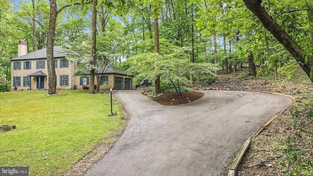 view of front of property featuring aphalt driveway, a chimney, a front yard, and stucco siding