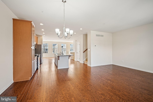 kitchen featuring visible vents, dark wood-type flooring, a notable chandelier, a center island with sink, and recessed lighting