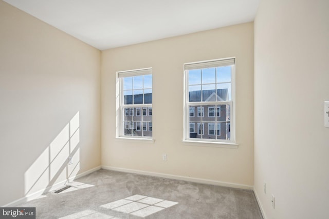 carpeted spare room with visible vents and baseboards