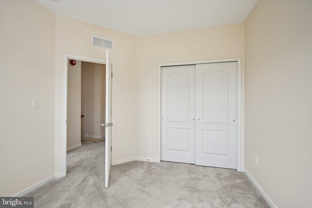 unfurnished bedroom with visible vents, light colored carpet, and baseboards