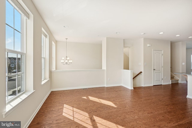 empty room with recessed lighting, a notable chandelier, baseboards, and dark wood-style flooring