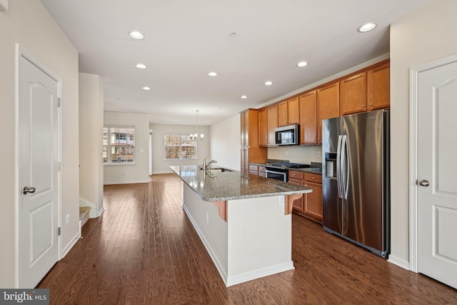 kitchen with a kitchen bar, brown cabinetry, dark wood-style flooring, and appliances with stainless steel finishes