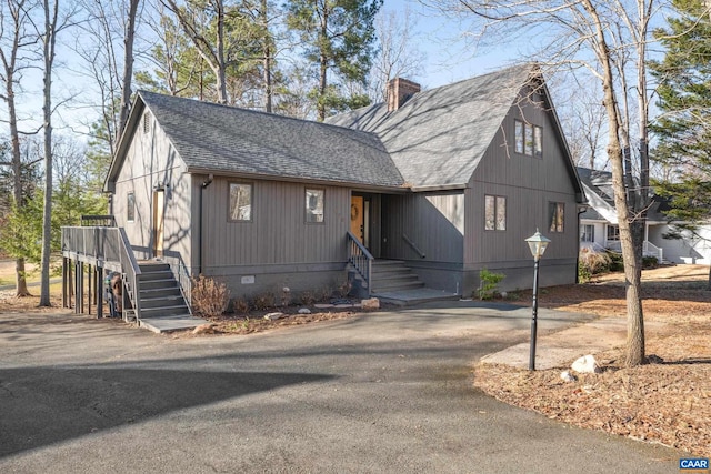 view of front of house featuring crawl space, a chimney, driveway, and a shingled roof