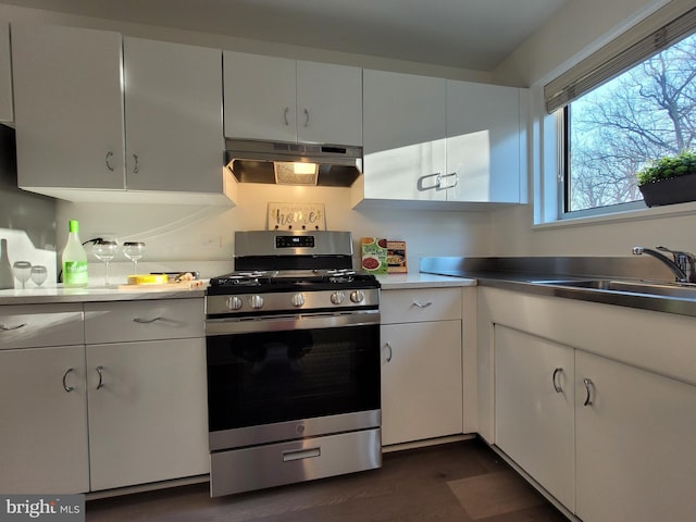 kitchen featuring dark wood finished floors, under cabinet range hood, white cabinets, and stainless steel gas range