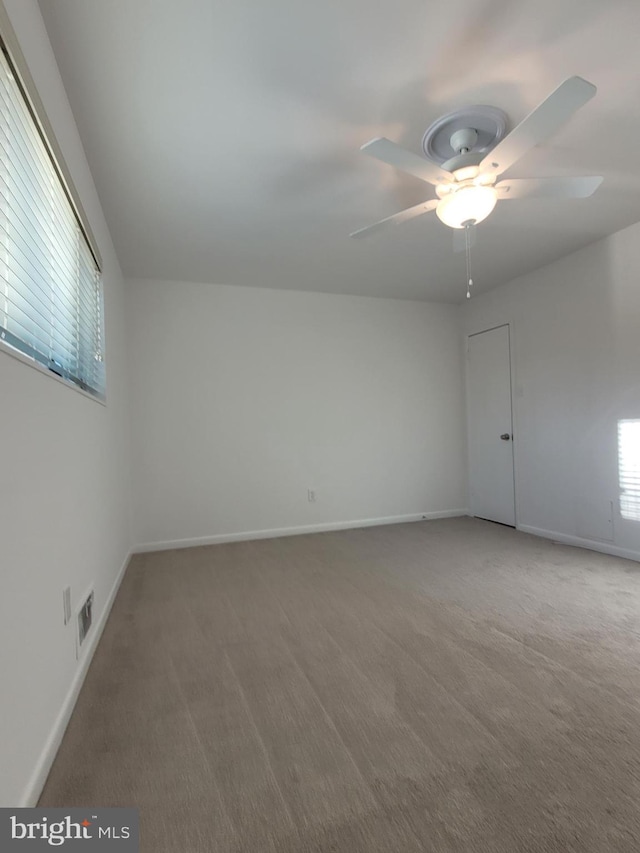 carpeted empty room with visible vents, ceiling fan, and baseboards