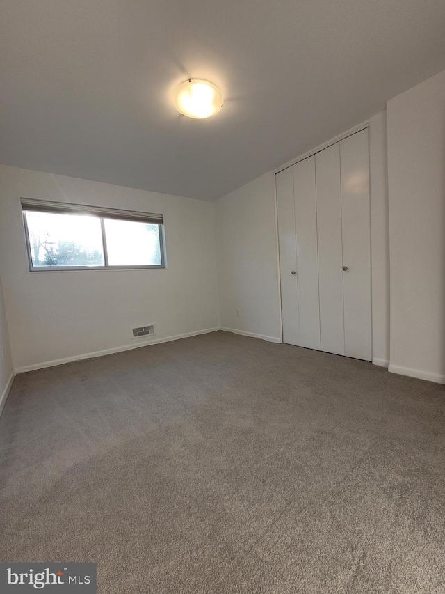 unfurnished bedroom featuring carpet, visible vents, a closet, and baseboards