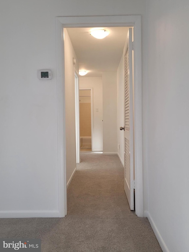 hallway featuring baseboards and carpet