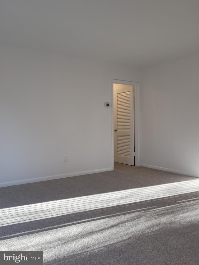 carpeted empty room featuring baseboards