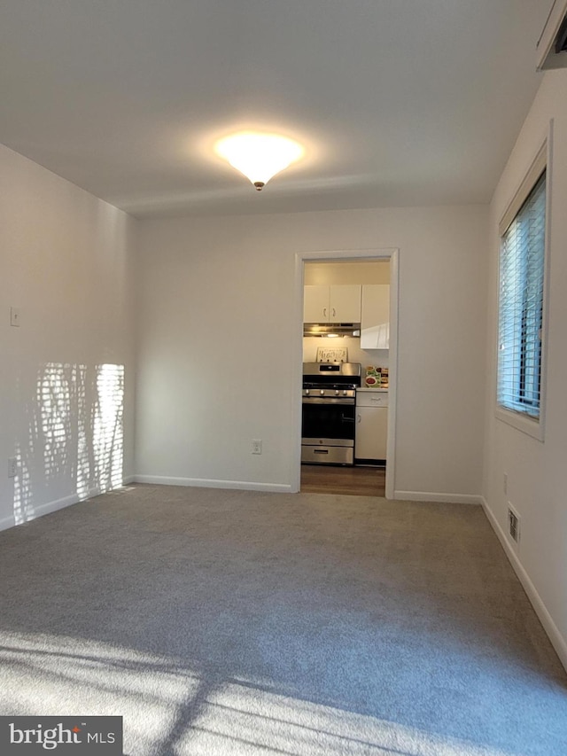 spare room with visible vents, dark carpet, and baseboards