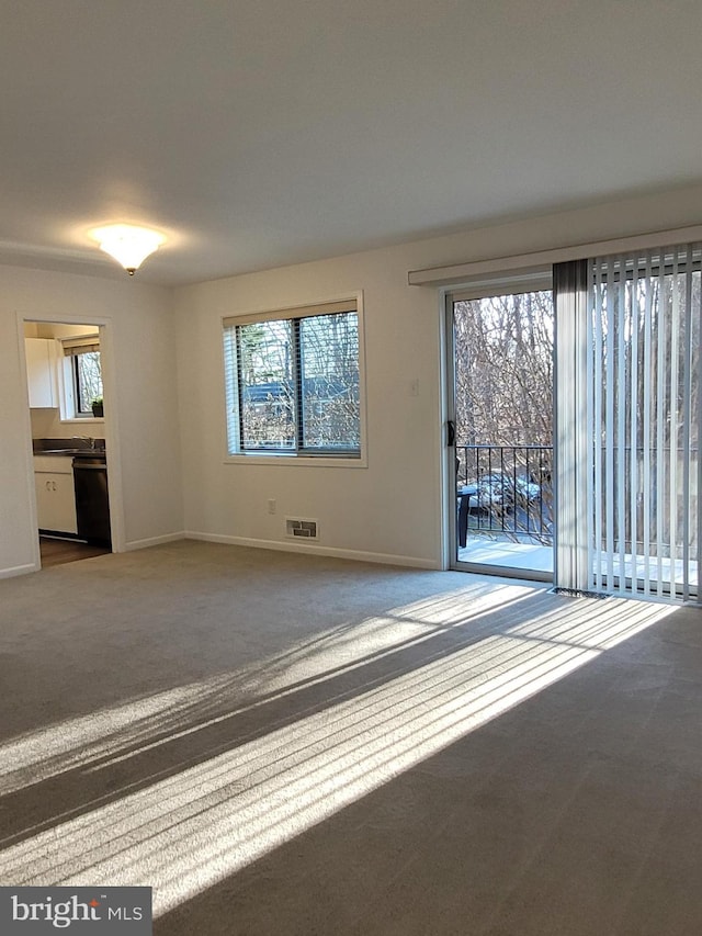 unfurnished room featuring visible vents, plenty of natural light, carpet, and baseboards